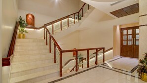 Un escalier en marbre avec des rampes en bois et un pot de fleurs placé sur le palier.