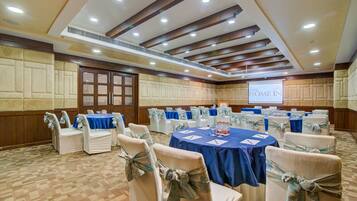 Un salón de conferencias con mesas redondas, sillas blancas y manteles azules.