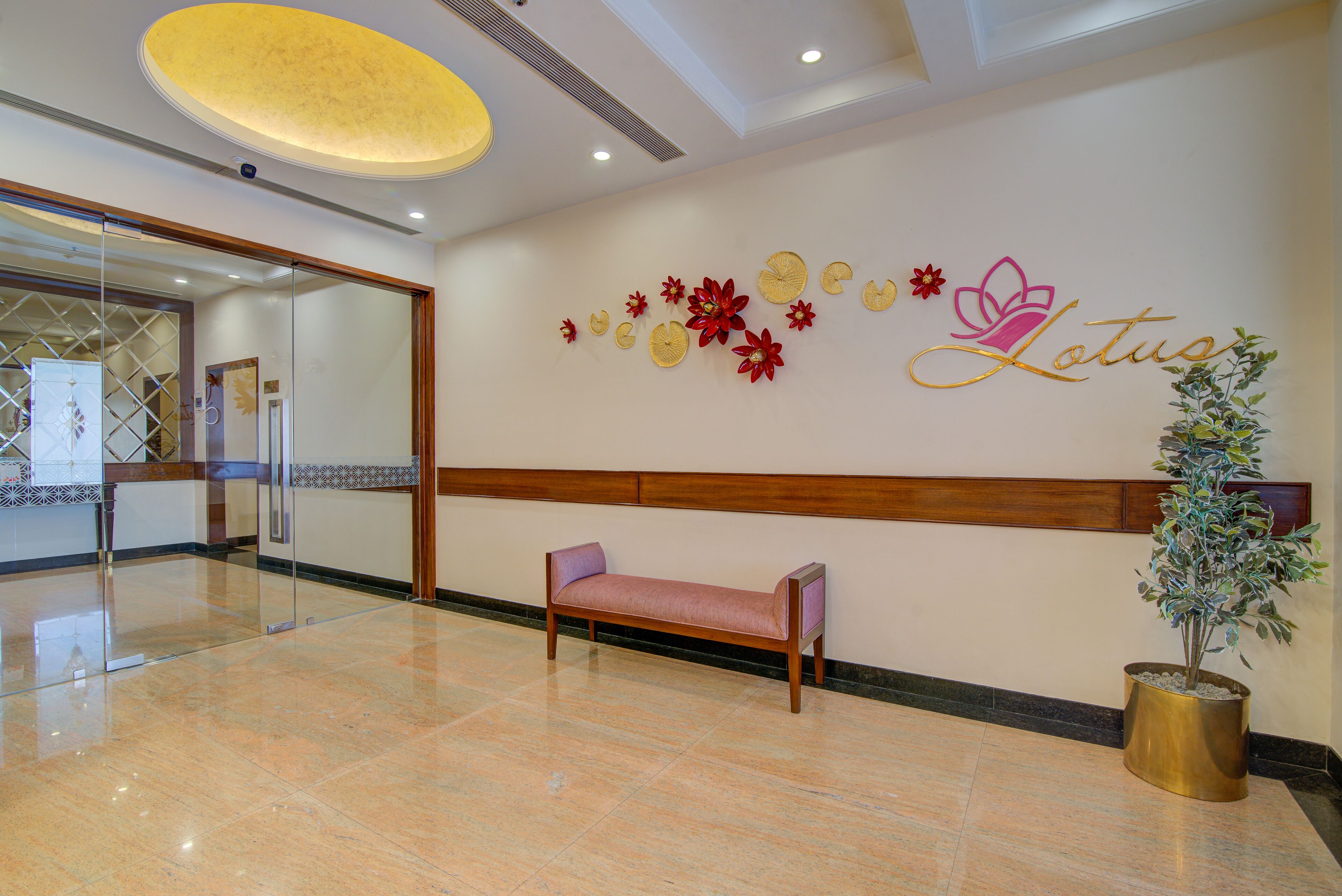 A lobby with a bench, a wall with floral decorations, and a potted plant.