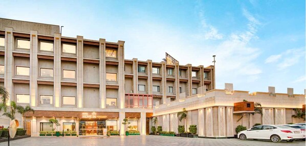 A modern hotel with a multi-story structure, a central entrance, and a parking area.