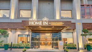 L’entrée d’un hôtel, avec une façade moderne, un aspect accueillant et des plantes en pot disposées dans les environs.