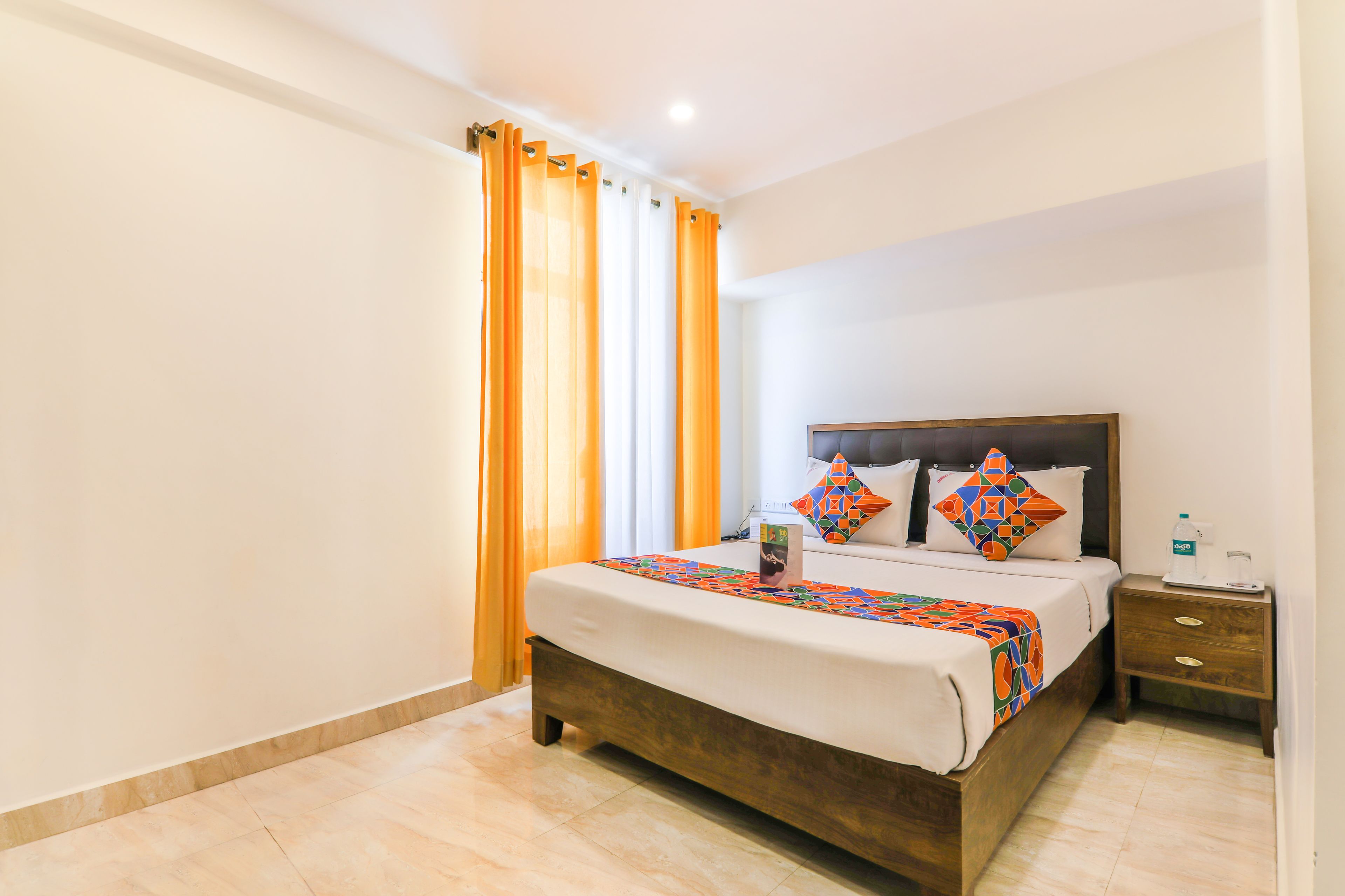 Une chambre d’hôtel avec un lit, des rideaux, une table de chevet et une petite table d’appoint.
