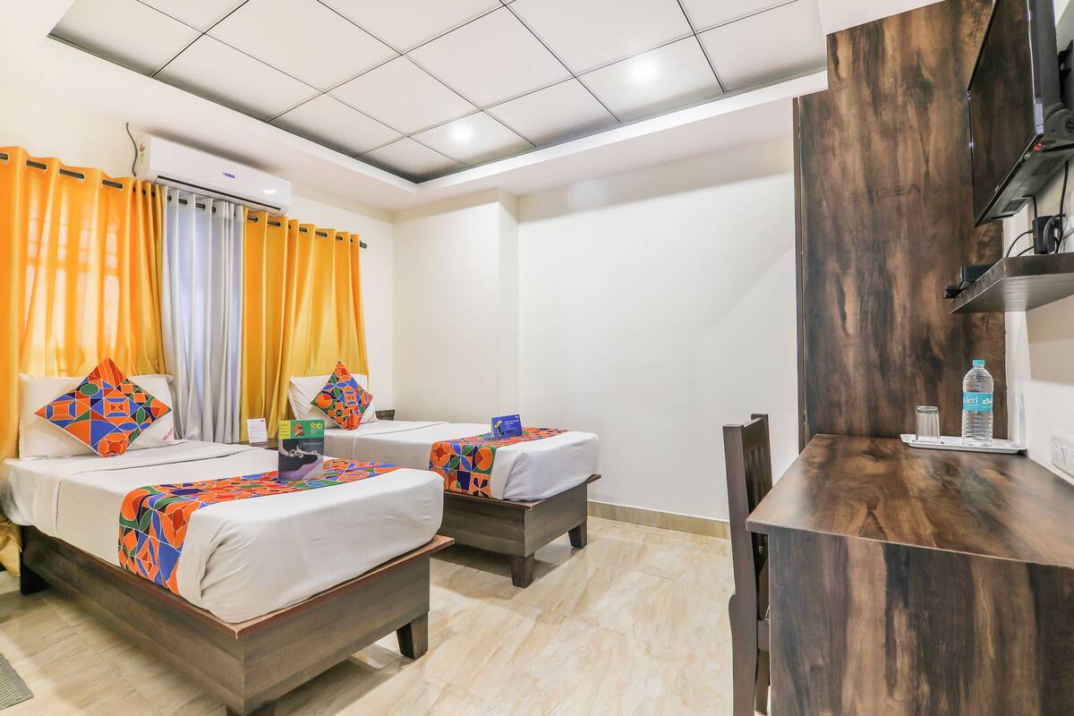 A hotel room with two beds, a desk, and a TV.