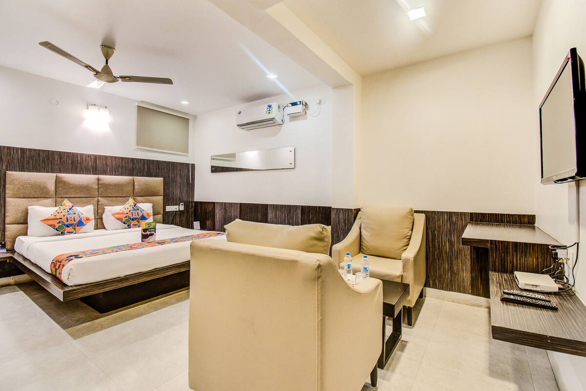 A hotel room with a bed, a sofa, a TV, and a ceiling fan.