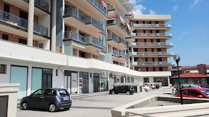 A multi-story hotel with balconies, a parking area, and a clear sky. - B&B Mediterraneo (Floridia)