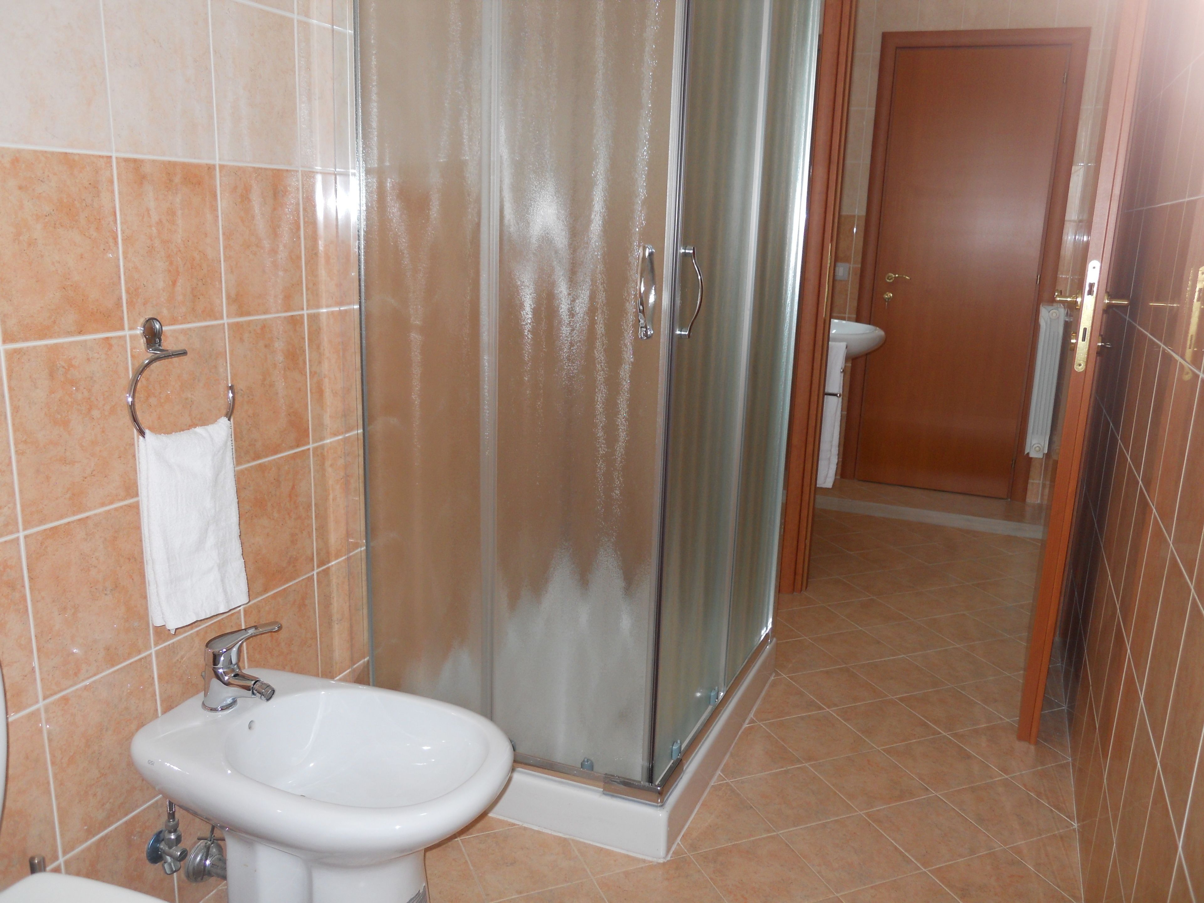 A bathroom with a glass shower enclosure, a sink, and a toilet.