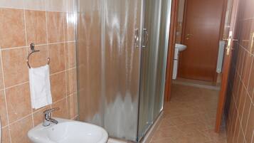 A bathroom with a glass shower enclosure, a sink, and a toilet.