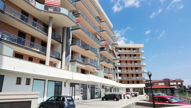 A multi-story hotel with balconies, a parking area, and a clear sky. - B&B Mediterraneo (Floridia)