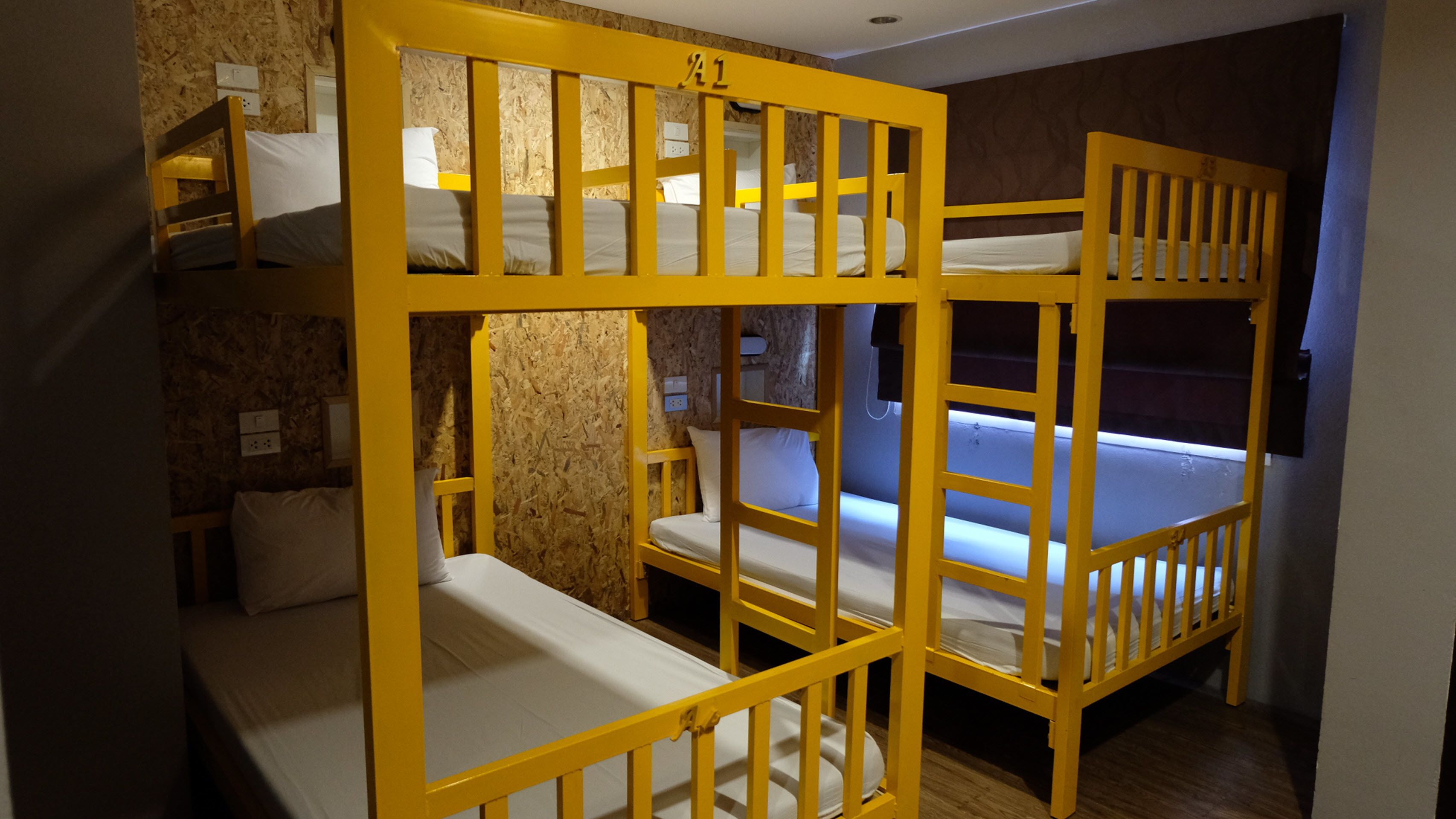 Une chambre avec des lits superposés, des têtes de lit en bois et une petite table de chevet avec une lampe.