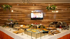 A buffet setup with various food items and a television screen displaying a program. - B Hotel Bishkek (Bishkek)