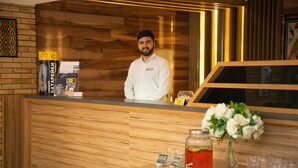 A reception desk with a wooden finish, a glass display case, and a vase with white flowers. - B Hotel Bishkek (Bishkek)