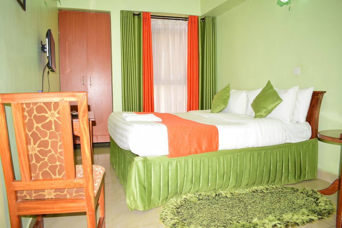 Un dormitorio con una cama, una silla, una mesita y una ventana con cortinas.