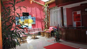 Un espacio interior acogedor, con una pared roja, un sofá, una mesa y una recepción.