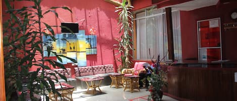 A cozy indoor space with a red wall, a sofa, a table, and a reception desk.