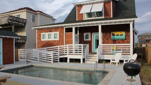 A house with a pool, a barbecue grill, and outdoor seating.