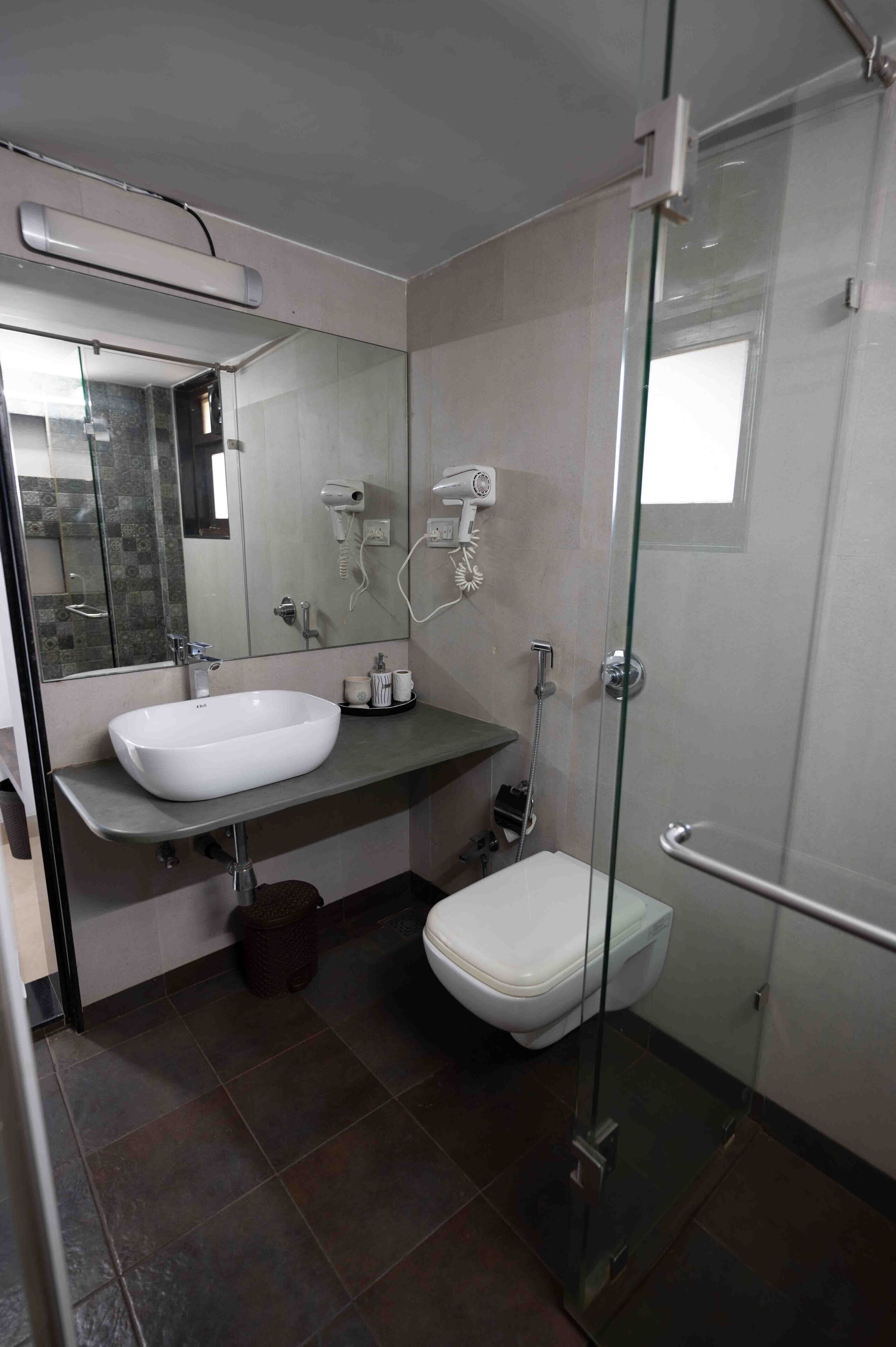 A modern bathroom with a glass shower enclosure, a white sink, and a toilet.