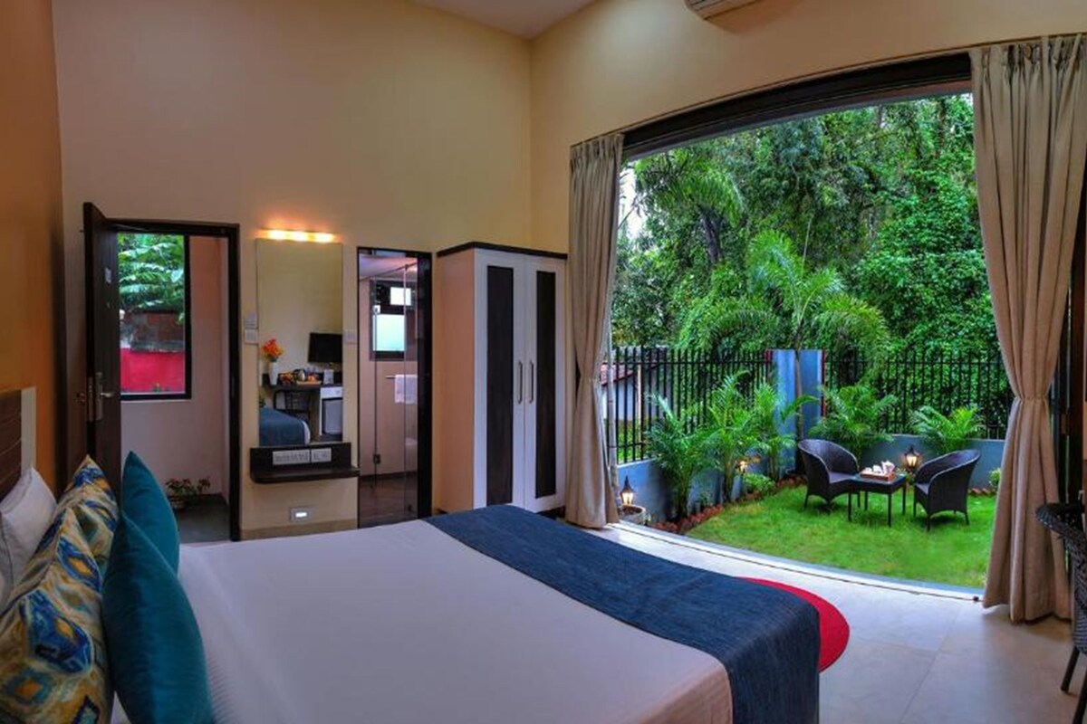 Habitación de hotel con cama, televisión, escritorio y vista a un jardín.