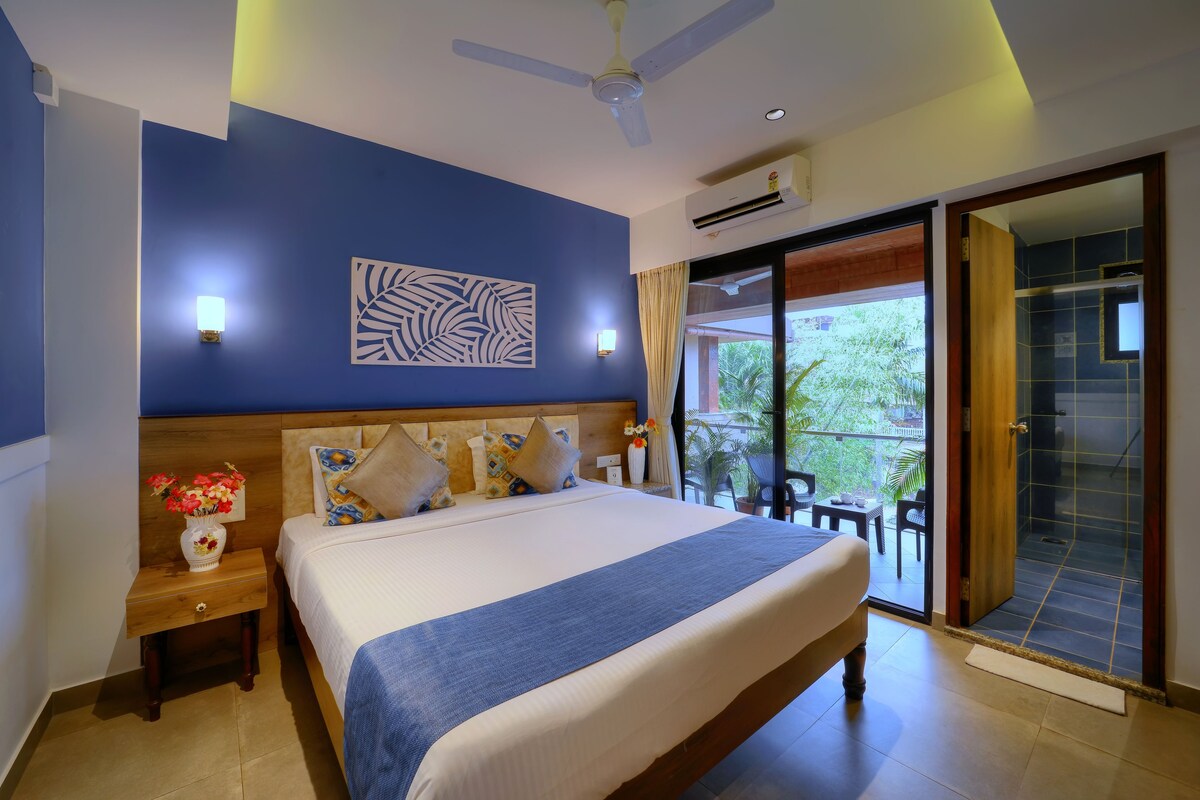 Un dormitorio con cama, mesita de noche, decoración mural y una puerta corrediza de vidrio que da a un espacio exterior.