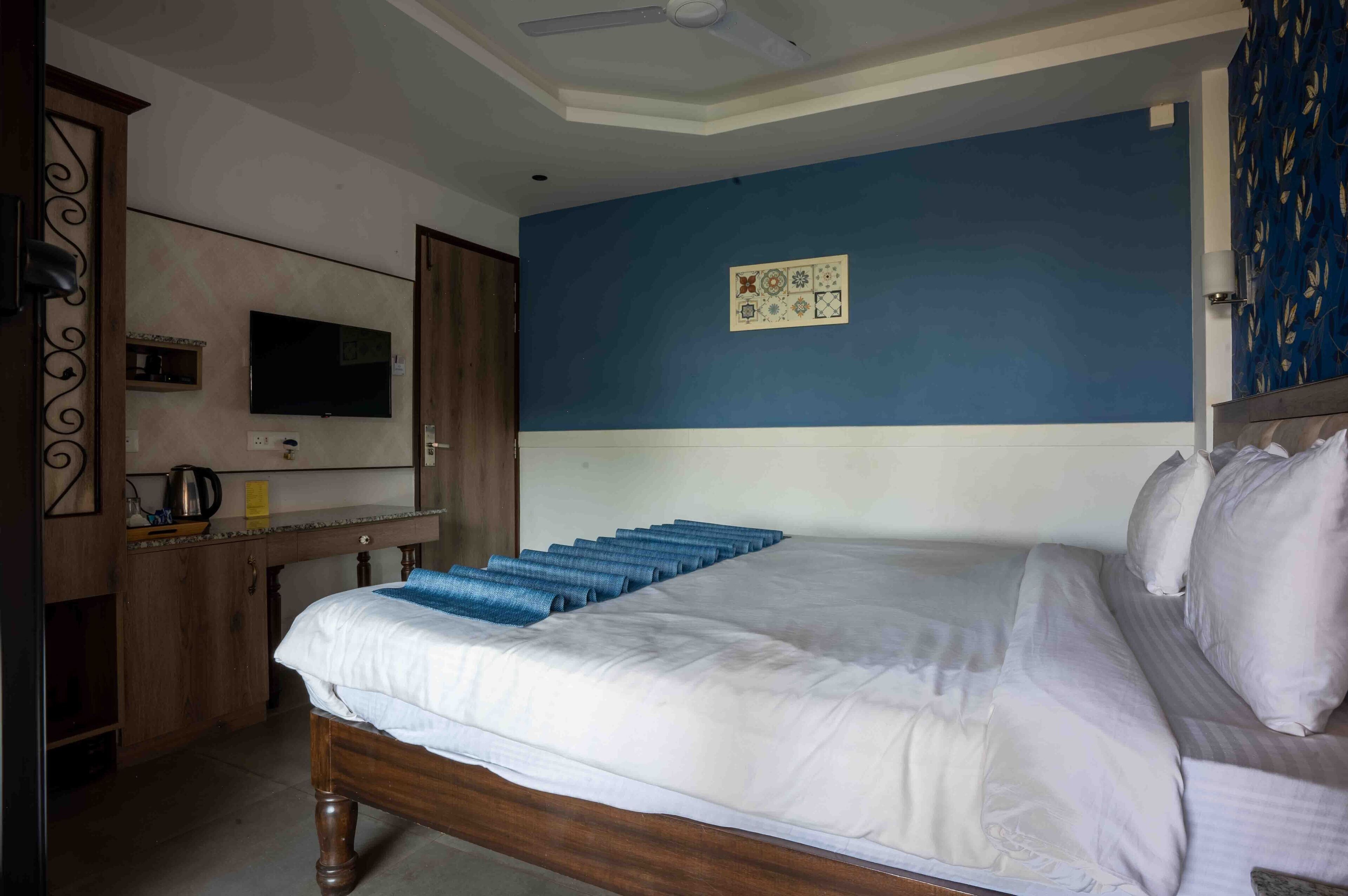A hotel room with a bed, a television mounted on the wall, and a ceiling fan.
