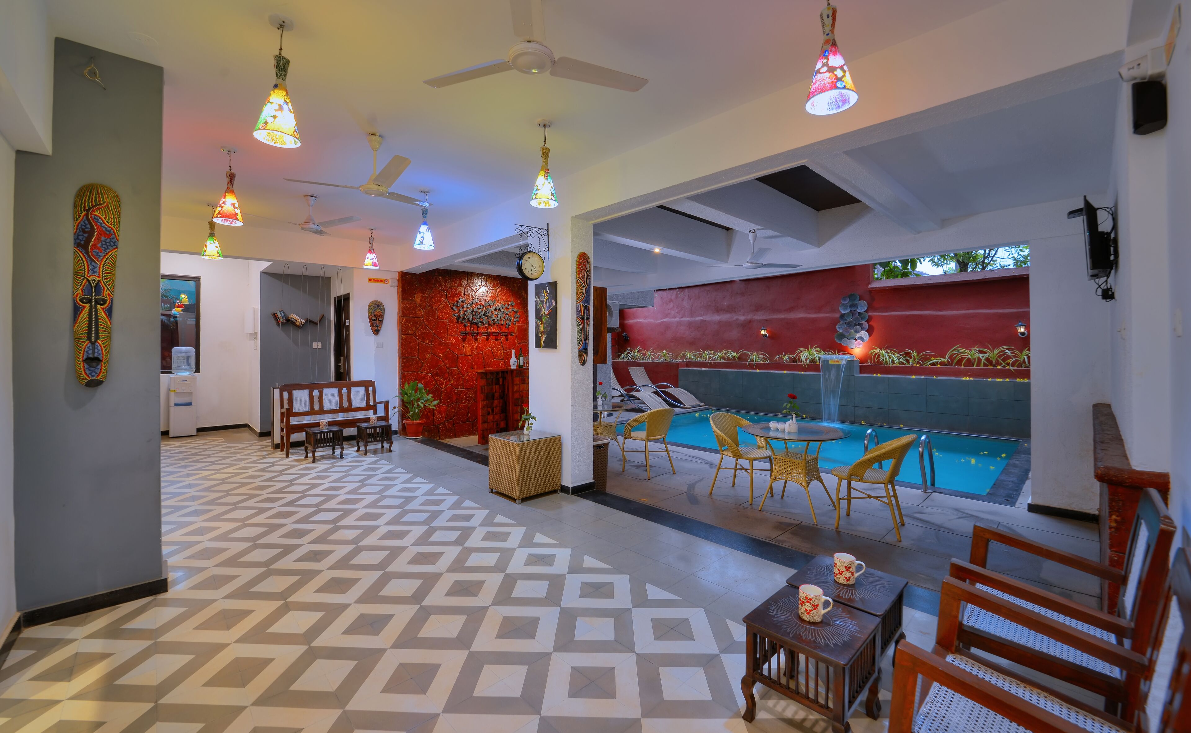 Un vestíbulo de hotel con mostrador de recepción, zona de estar y piscina con tumbonas.