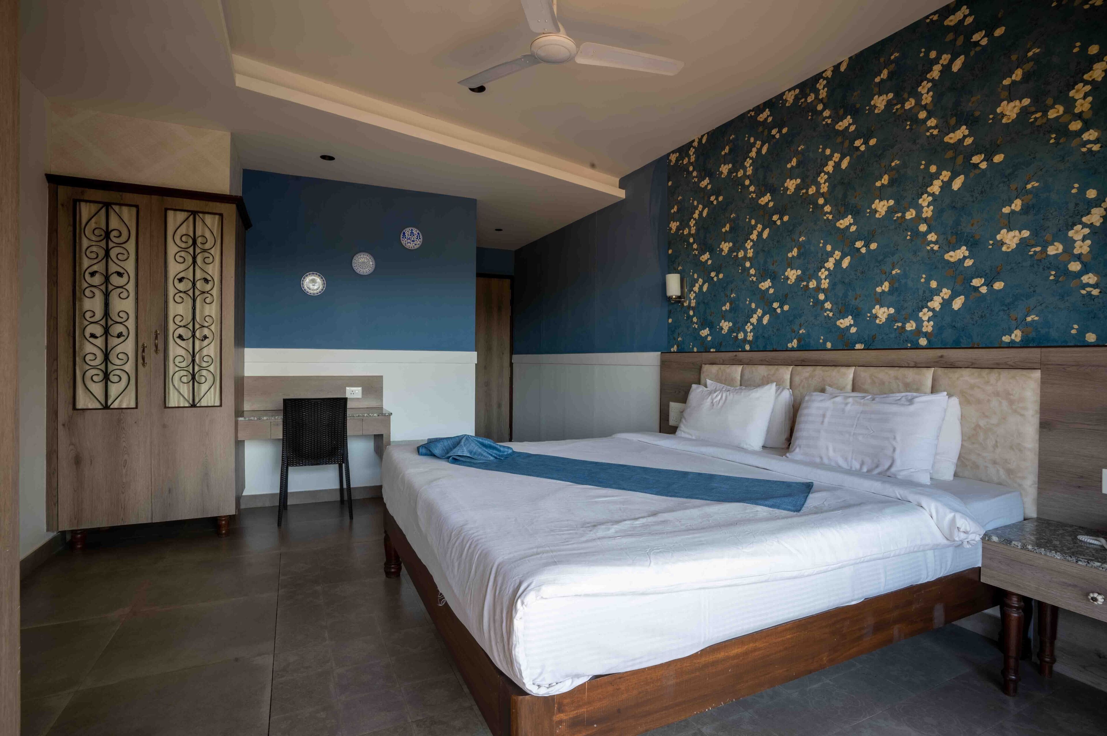 A hotel room with a large bed, a desk, and a wardrobe.
