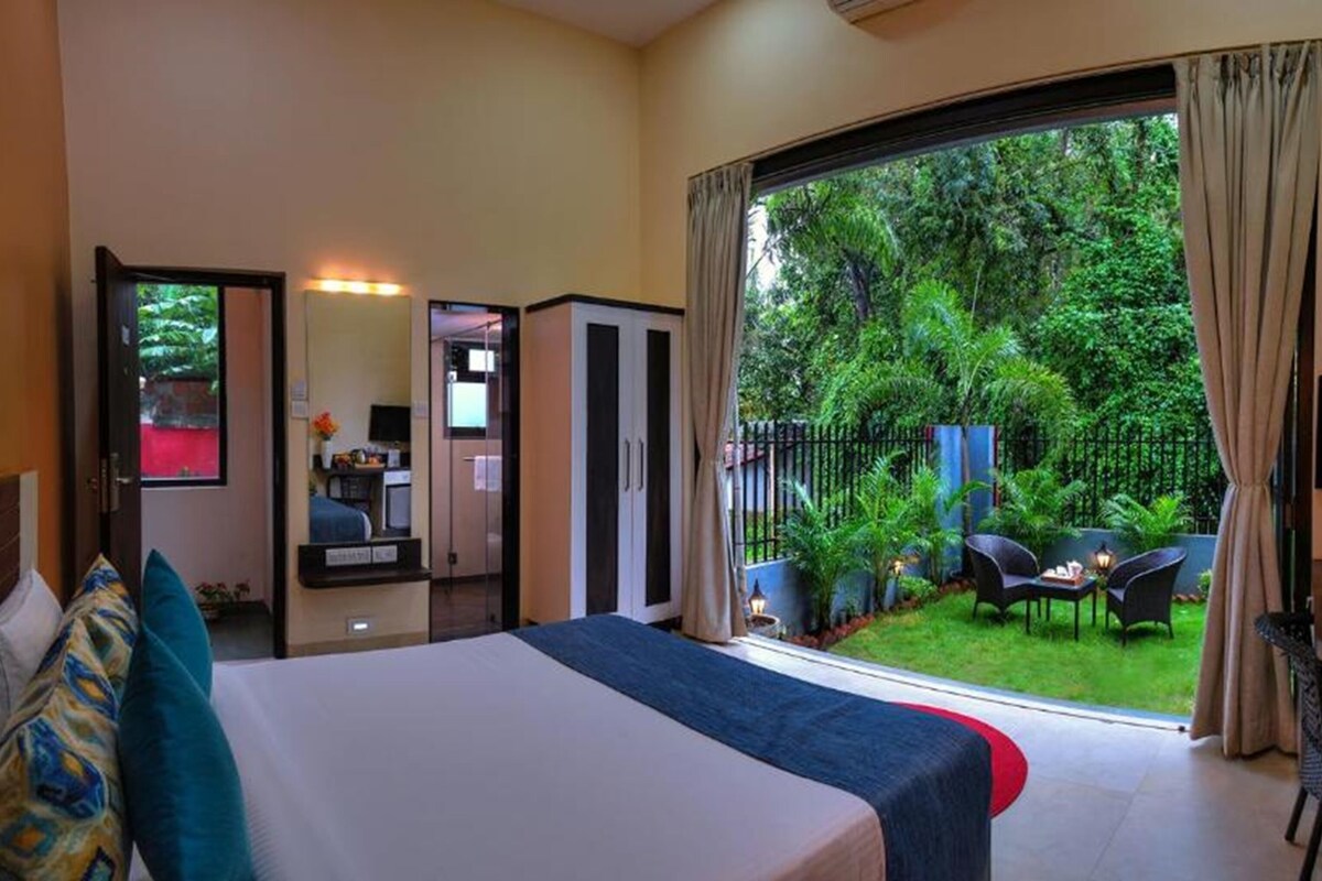 Une chambre d’hôtel avec un lit, une télévision, un bureau et une vue sur un jardin.