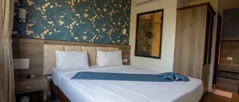 Una habitación de hotel con una cama grande, un cabecero de madera, una mesita de noche, una lámpara de pared y un armario.