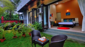 Una habitación de hotel moderna con una cama, una mesita con una bandeja y una silla. Hay plantas en macetas fuera de la habitación.