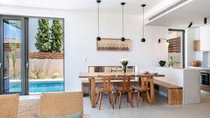 A modern kitchen with a dining area, a pool view, and a large sliding glass door. - Fos Villa your place under the Cretan Sun with private heated pool (Chania)