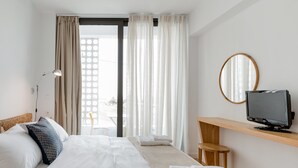 A hotel room with a bed, a TV on a wooden shelf, a mirror, and a view of the outdoors. - Fos Villa your place under the Cretan Sun with private heated pool (Chania)
