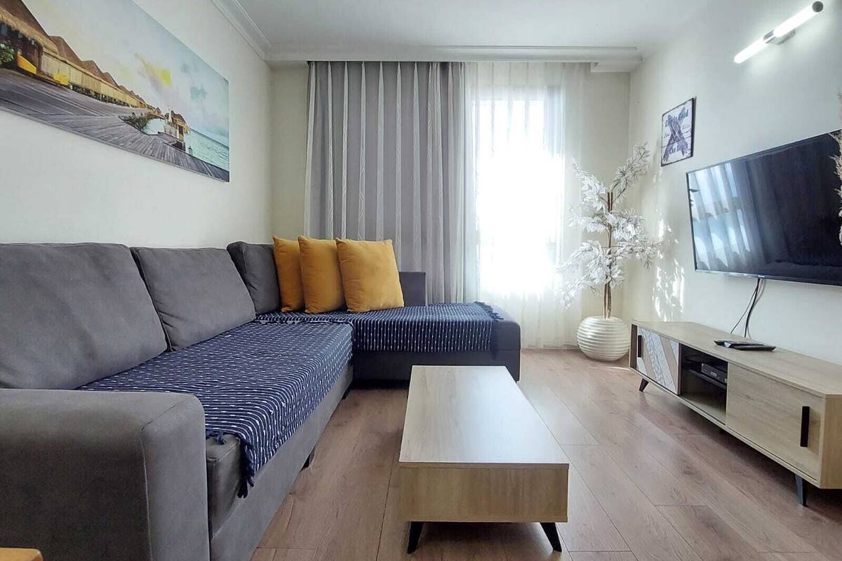 Un salon moderne avec un canapé, une table basse, un téléviseur et un tableau accroché au mur.