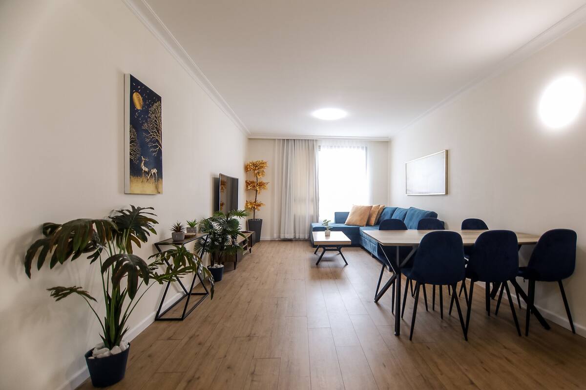 Un salon moderne comprenant un canapé, une table à manger, des chaises et des plantes en pot.