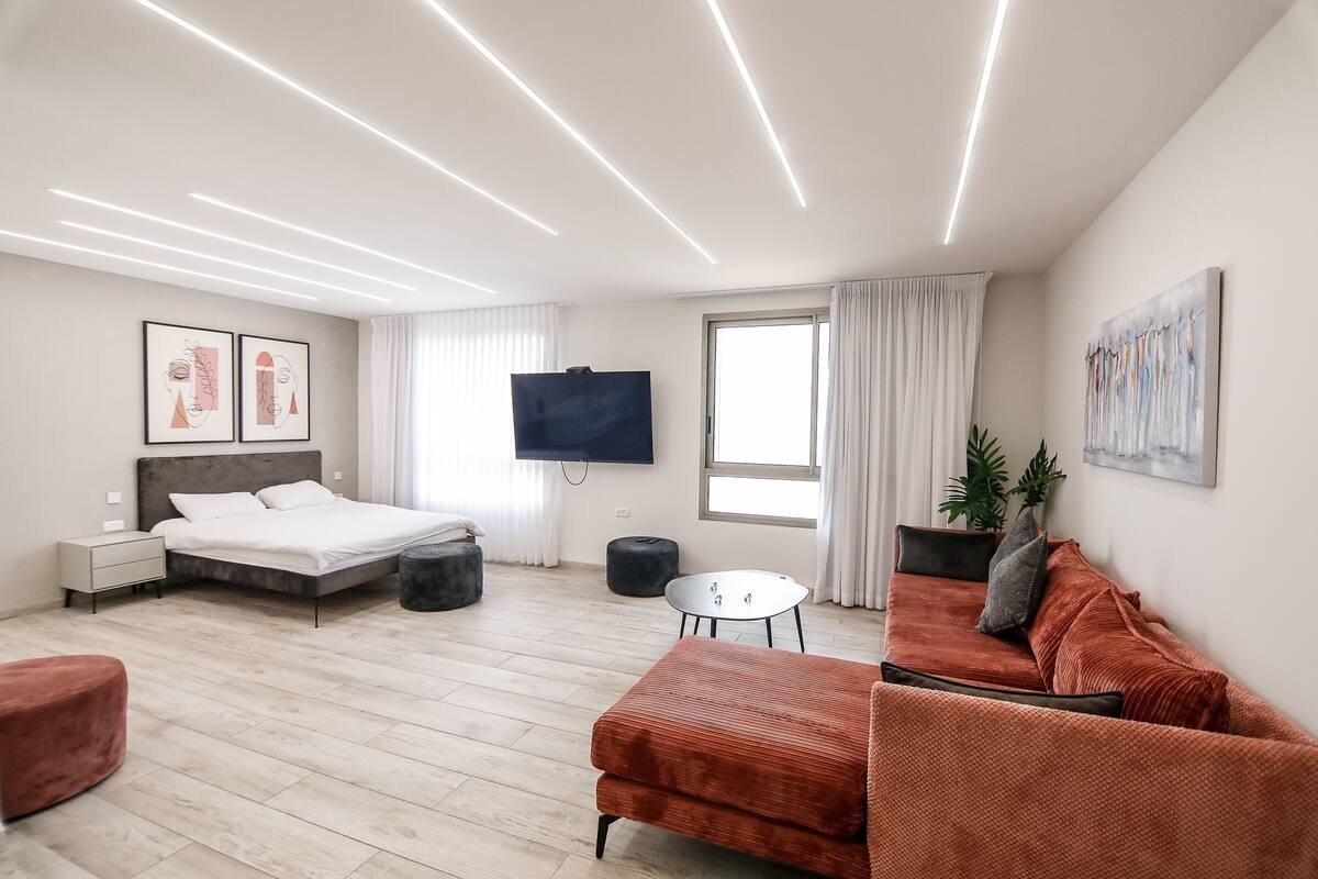 Une chambre d’hôtel moderne équipée d’un lit, d’un canapé, d’une télévision et d’une fenêtre.