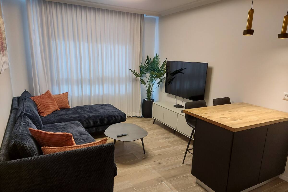 Un salon moderne avec un canapé, une table basse et un petit îlot en bois.