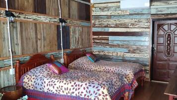 A room with two wooden beds with patterned bedding, a rustic wooden wall, and a wooden door.