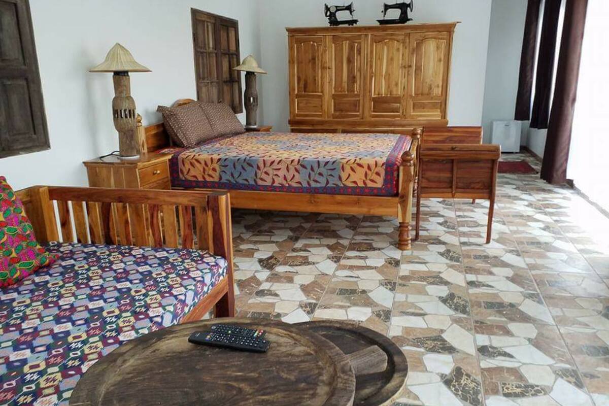 Une pièce comprenant un lit, une armoire en bois, une chaise, une petite table et une lampe.