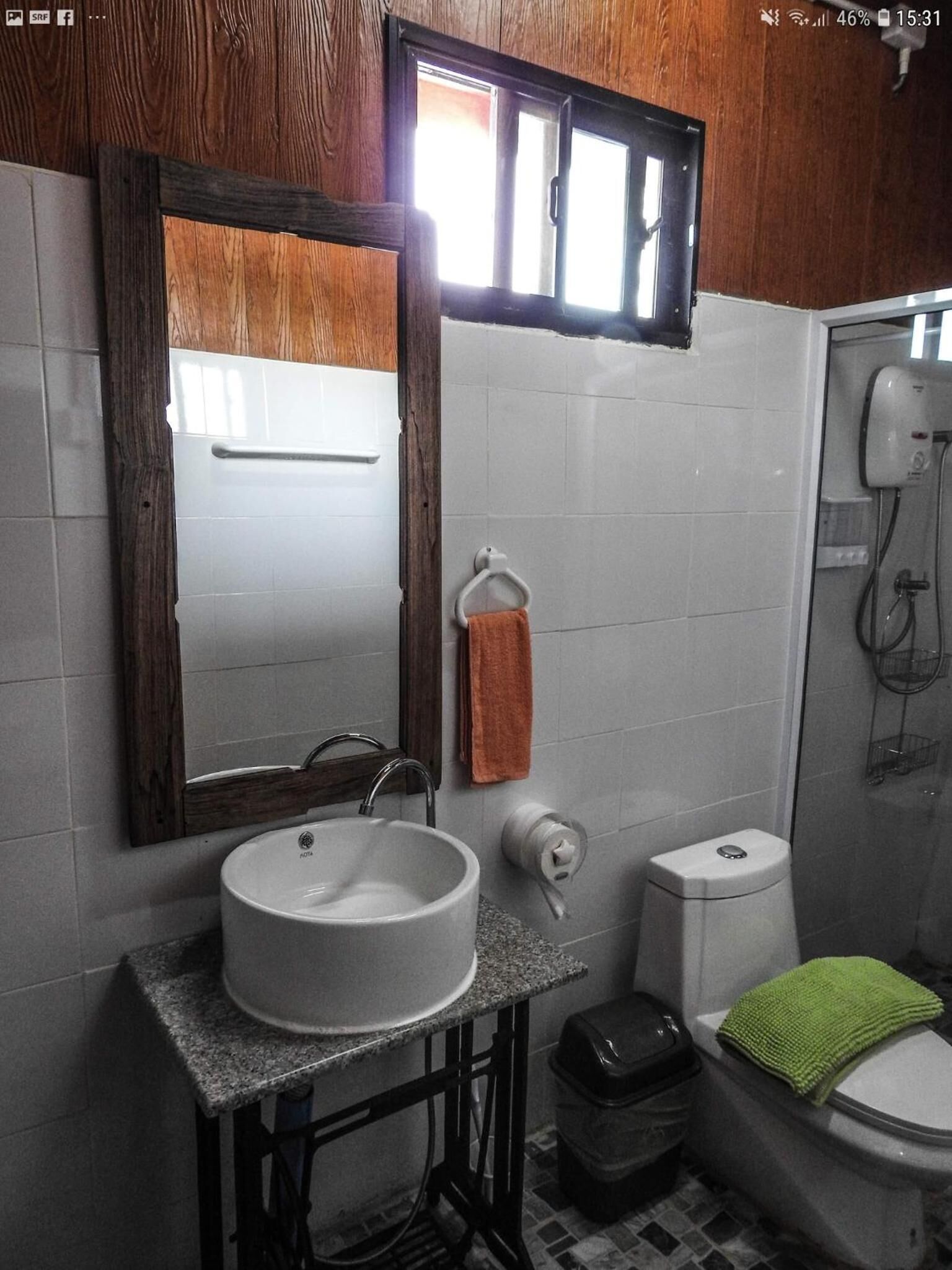 Et badeværelse med en trækommode, en hvid vask, et håndklædestativ, et toilet og et bruseområde.