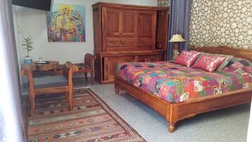 Une chambre à coucher avec un lit en bois, un bureau, une chaise, une armoire et un tapis à motifs.