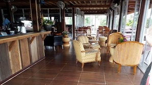 A spacious indoor area with wooden flooring, several wicker chairs, and a bar area with a counter. - Coffee&Homestay568 Branch 2 (Muang Suang)