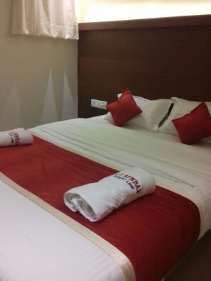 Ein Hotelzimmer mit einem Bett, rot-weiß gestreifter Bettwäsche und einem hölzernen Kopfteil.