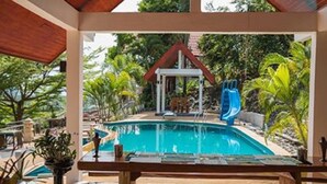 A pool area with a slide, surrounded by tropical plants and a covered seating area. - Krabi Villa Phu Khao Private Resort (Krabi)