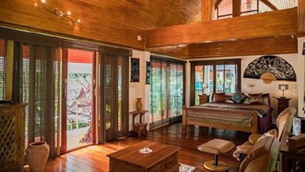 A spacious room with a large bed, wooden flooring, and a view through a sliding door. - Krabi Villa Phu Khao Private Resort (Krabi)