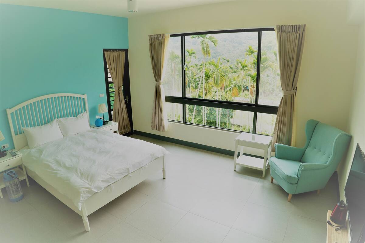 Una habitación de hotel con cama, una silla, un televisor y una ventana con cortinas.