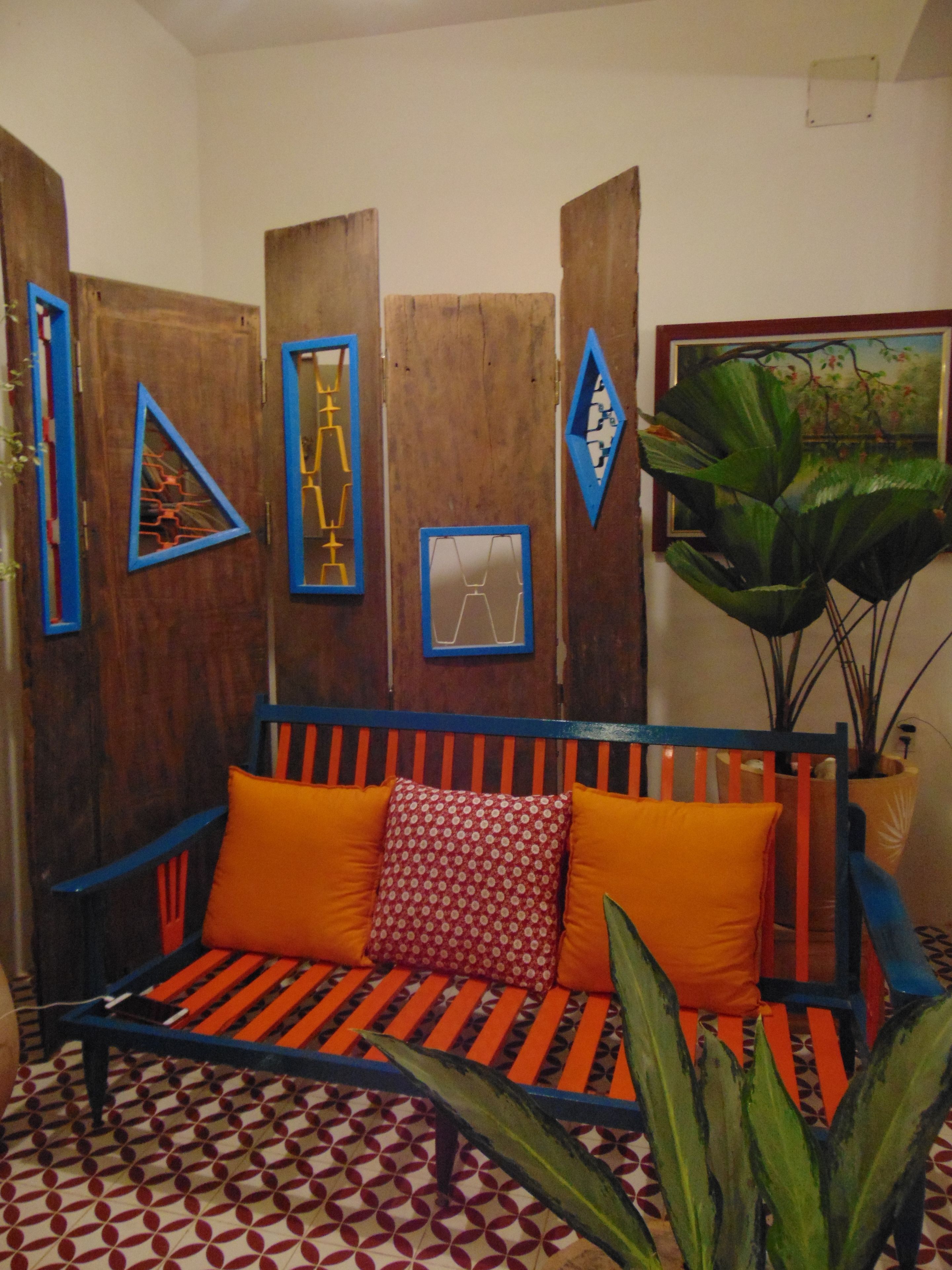 A room with a wooden partition, a blue and orange sofa, and a large plant.