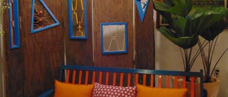A room with a wooden partition, a blue and orange sofa, and a large plant.