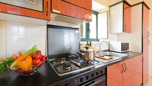 A kitchen with a gas stove, a microwave, and a sink. There is a bowl of vegetables on the counter. - House / Villa - Giarre (Giarre)
