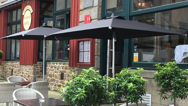 A hotel with outdoor seating, stone walls, and a restaurant sign. - Hotel Armoricaine (Saint-Malo)