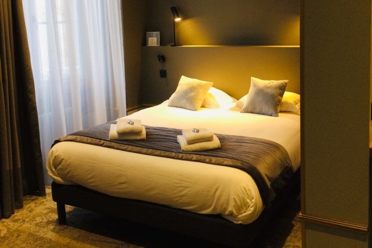 A modern hotel room with a large bed, a bedside table, and a nightstand.