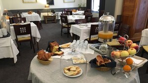 A breakfast buffet with bread, pastries, fruits, and a juice dispenser. - Hotel Armoricaine (Saint-Malo)