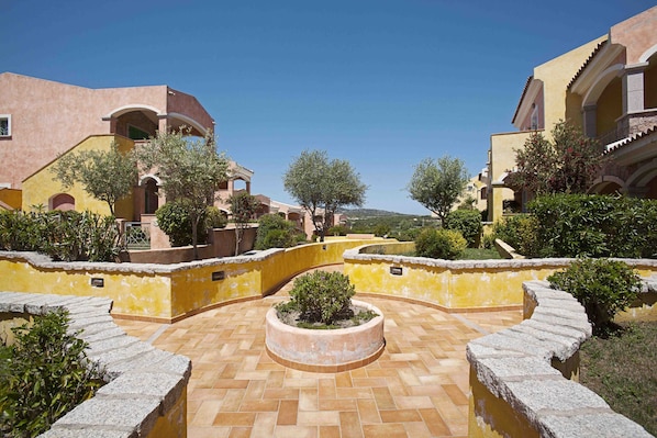 A courtyard with a circular garden, yellow walls, and a tiled floor.